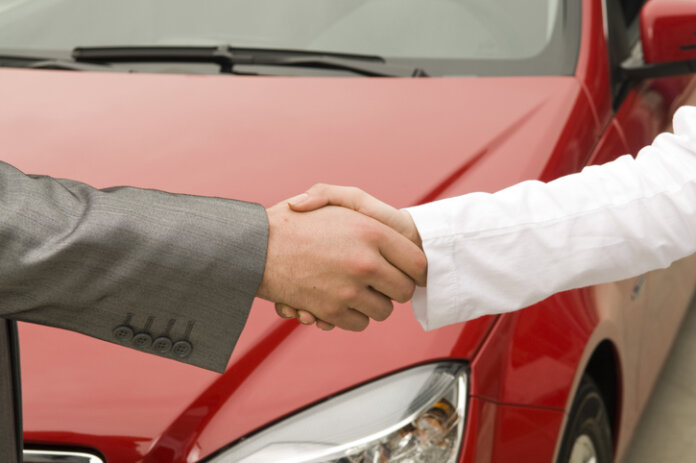 Händeschütteln für Kauf von Gebrauchtwagen vor Auto